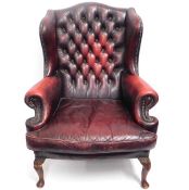 An oxblood red wing back Chesterfield style arm ch