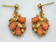 A pair of yellow metal earrings of organic design, electronically test as 14ct gold, set with coral,