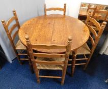 A circular pine table with four rush seated ladder