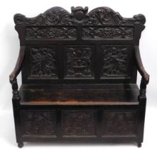 An antique carved oak monks bench with two 'Green