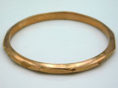 A 9ct gold bangle with machined decor to the facet