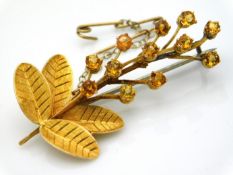 A yellow metal floral brooch set with citrine, indistinctly marked, tests electronically as 18ct gol