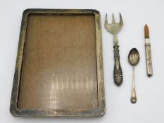 A silver photo frame, a silver pencil holder, an A. J. Bailey silver teaspoon 1907 & a silver handle
