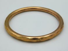 A Chester 9ct gold bangle with faceted decor, some