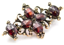 A yellow metal brooch set with garnet & seed pearl, some losses, 38mm wide, tests electronically as