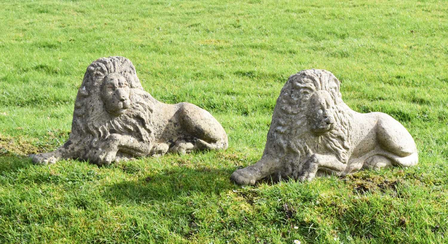 Pair of composite stone garden lions in recumbent posture