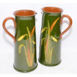 Pair of large antique pottery water jugs in a Torquay ware style with daffodil decoration. 26cms