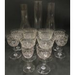 Three vintage glass oil lamp chimneys together with a collection of etched stemmed drinking glasses.