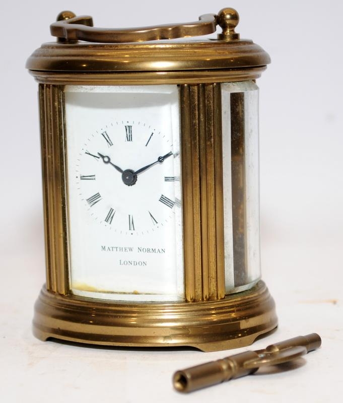 Quality Matthew Norman miniature oval carriage clock with key. Seen working. All bevelled glass