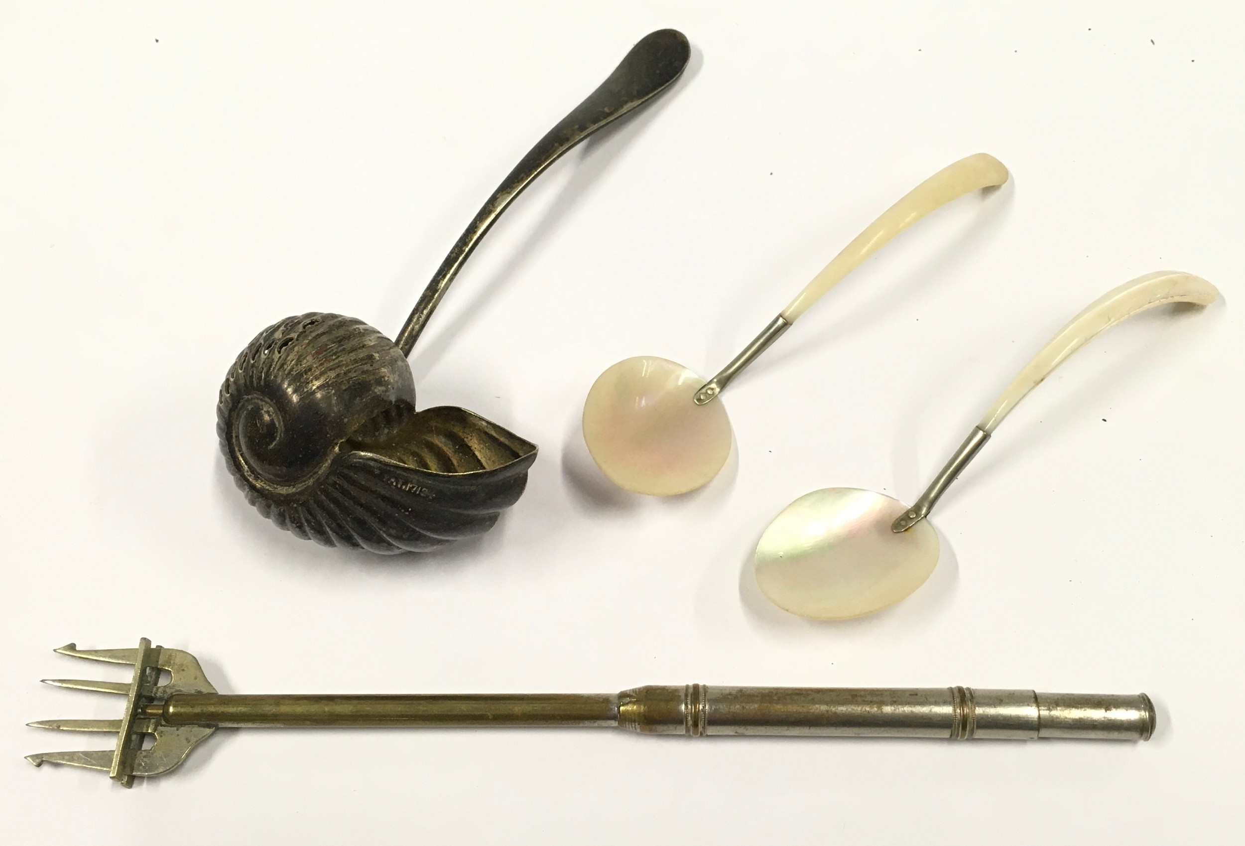 Silver plated snail ladle together with a pair of mother of pearl teaspoons and a fork.