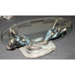 Large glass topped oval coffee table featuring a bronzed resin base depicting mermaids 44cms tall