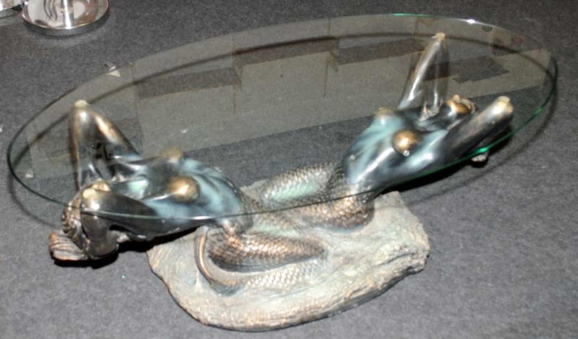 Large glass topped oval coffee table featuring a bronzed resin base depicting mermaids 44cms tall