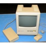 A Macintosh Plus with mouse and disc drive.