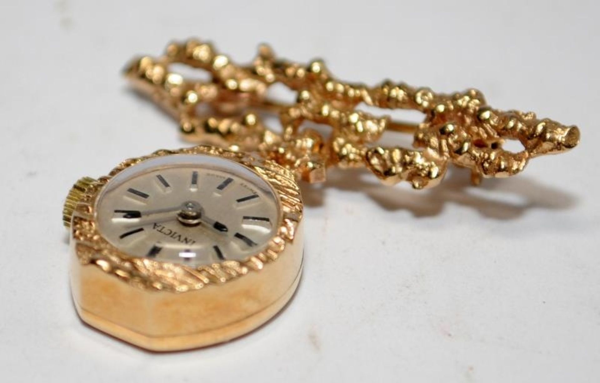 9ct gold brooch watch by Invicta. Watch winds and runs