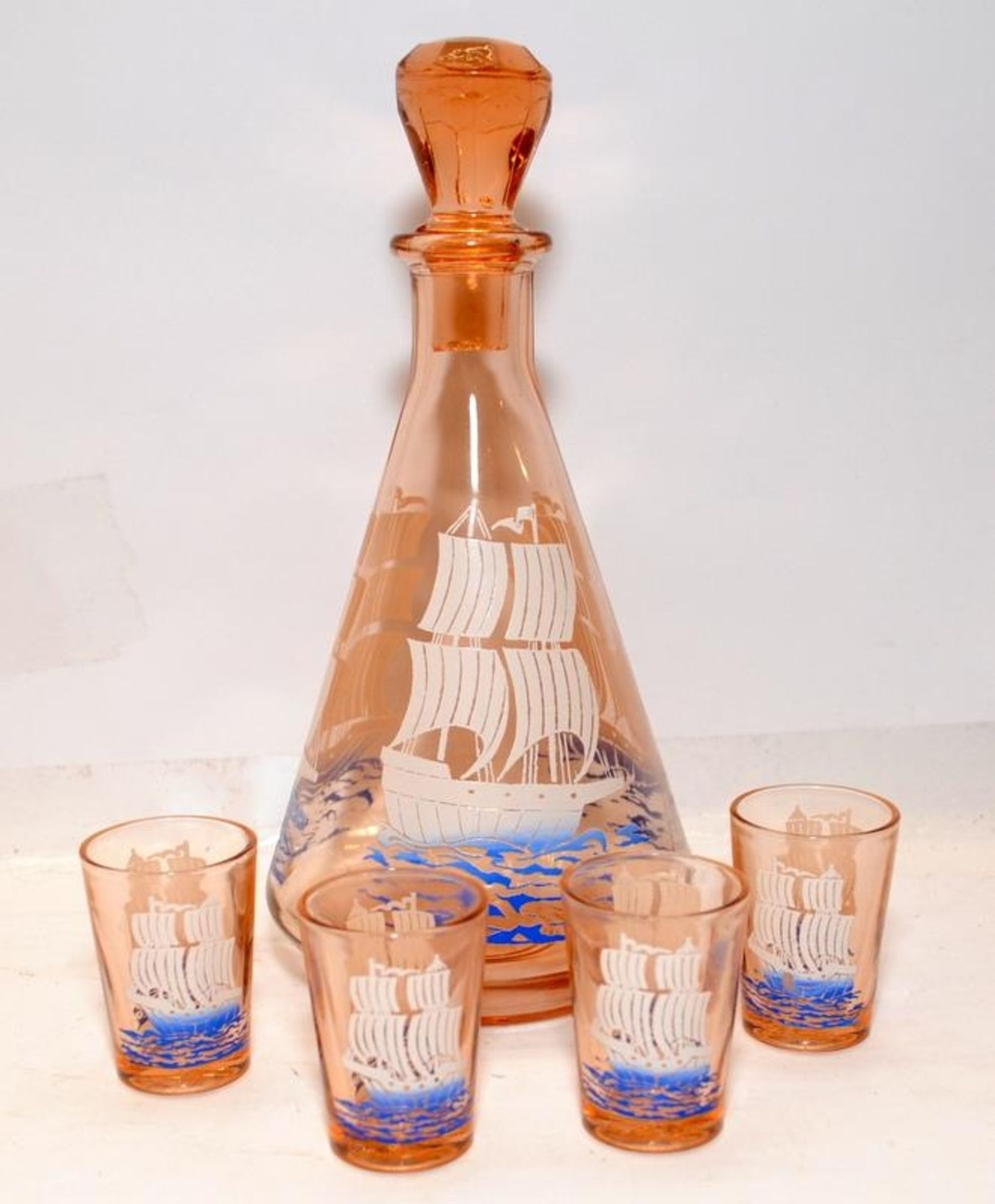Vintage mid-century peach glass decanter featuring a ship c/w four shot glasses