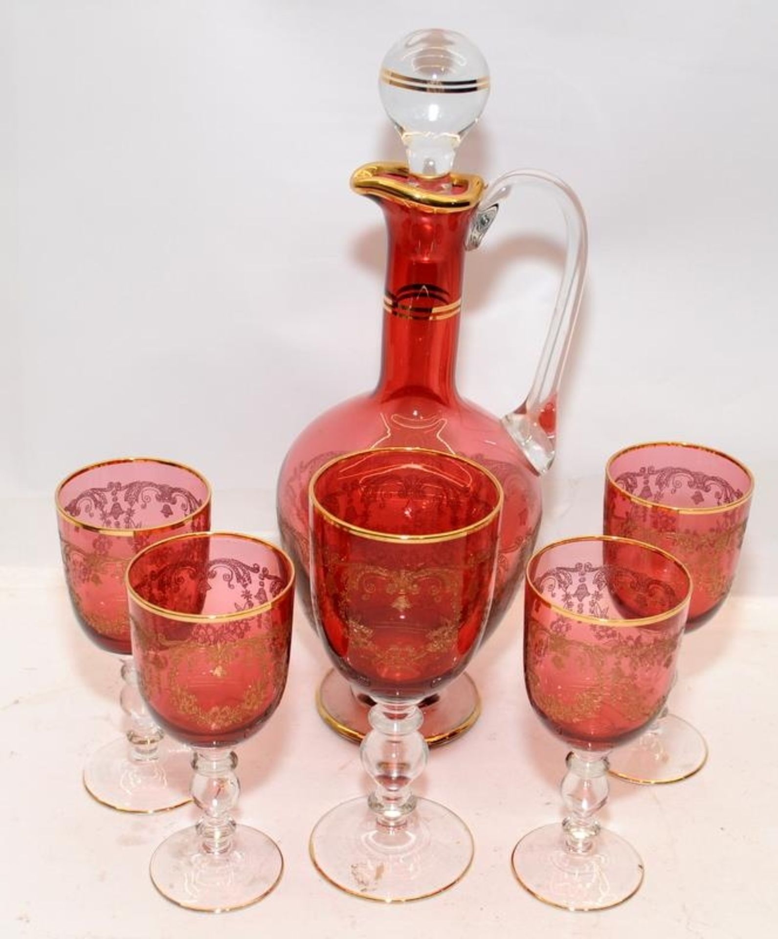 Vintage French rouge glass with gilded accents decanter with one large and four small goblets.