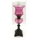 Victorian cranberry glass oil lamp on cast iron base 64cm tall.
