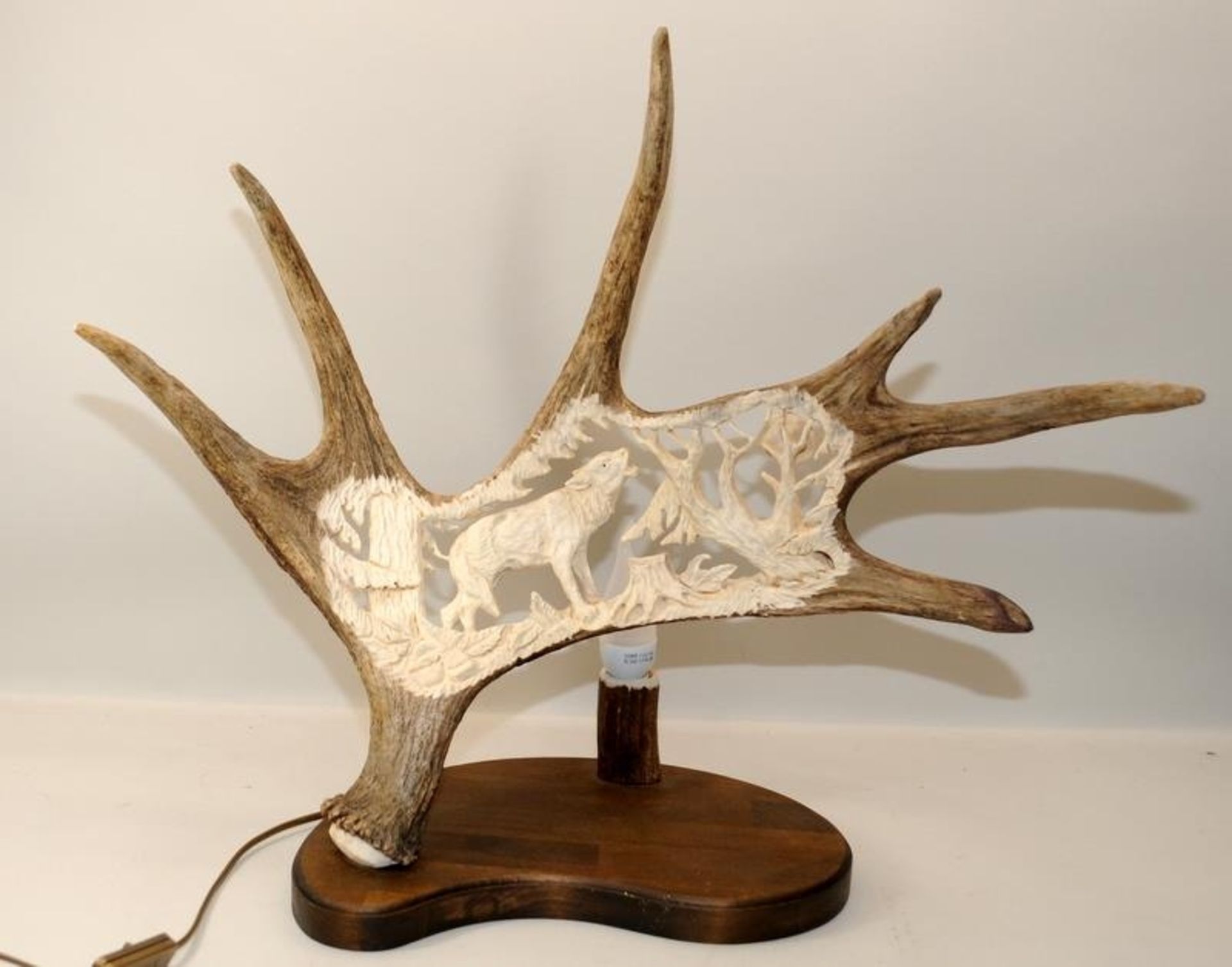 Large antler horn with incised carving depicting a howling wolf. Mounted on a wooden base and