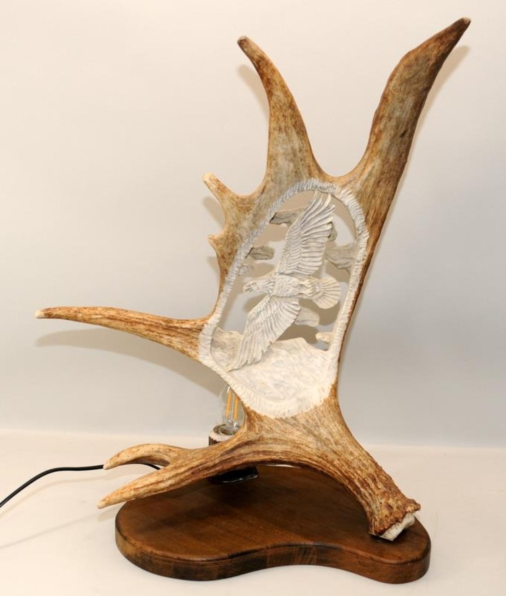 Large antler horn with incised carving depicting an eagle. Mounted on a wooden base and