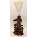 Black Forest carved centrepiece of a woodland scene with deer holding a cut glass trumpet vase. O/