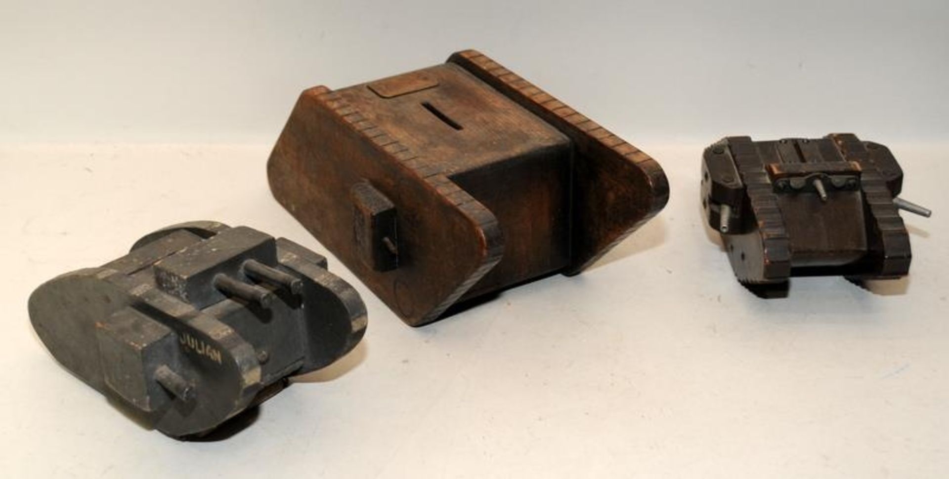 Three scratch built wooden money boxes in the form of WWI tanks the largest being 32cms across