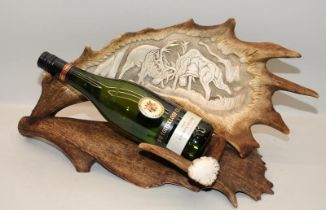 Antler with carved decorative scene fashioned as a bottle holder