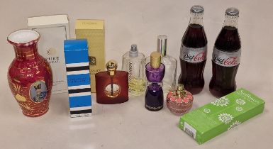 A collection of perfume bottles with two bottles of Diet Coke.