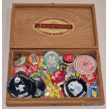Wooden cigar box containing a collection of vintage pin and enamel badges.