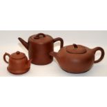 Three Chinese oriental Yixing pottery brown teapots, two of the having marks to the undersides.