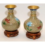 Pair of Oriental cloisonne decorated vases of smaller proportions on wooden stands 12cm tall