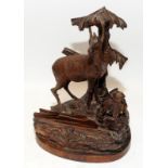 A vintage carved Black Forest inkwell and letter holder modelled as a stag in a forest setting.