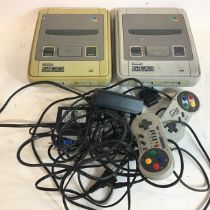 Super Nintendo entertainment systems x 2 with power supplies and wired hand held controllers.