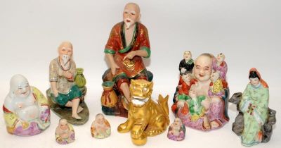 A collection of nine Chinese ceramic figures to include tradesman, buddhas, gilt foo lion and hooded