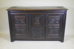 An C18th continental bog oak dresser/buffet with three cupboards and fielded carved panels with