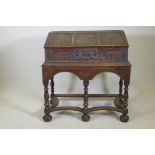A carved oak bible box on stand, with triple panel fall front, the stand raised on baluster turned