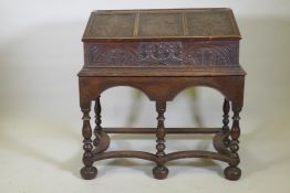 A carved oak bible box on stand, with triple panel fall front, the stand raised on baluster turned