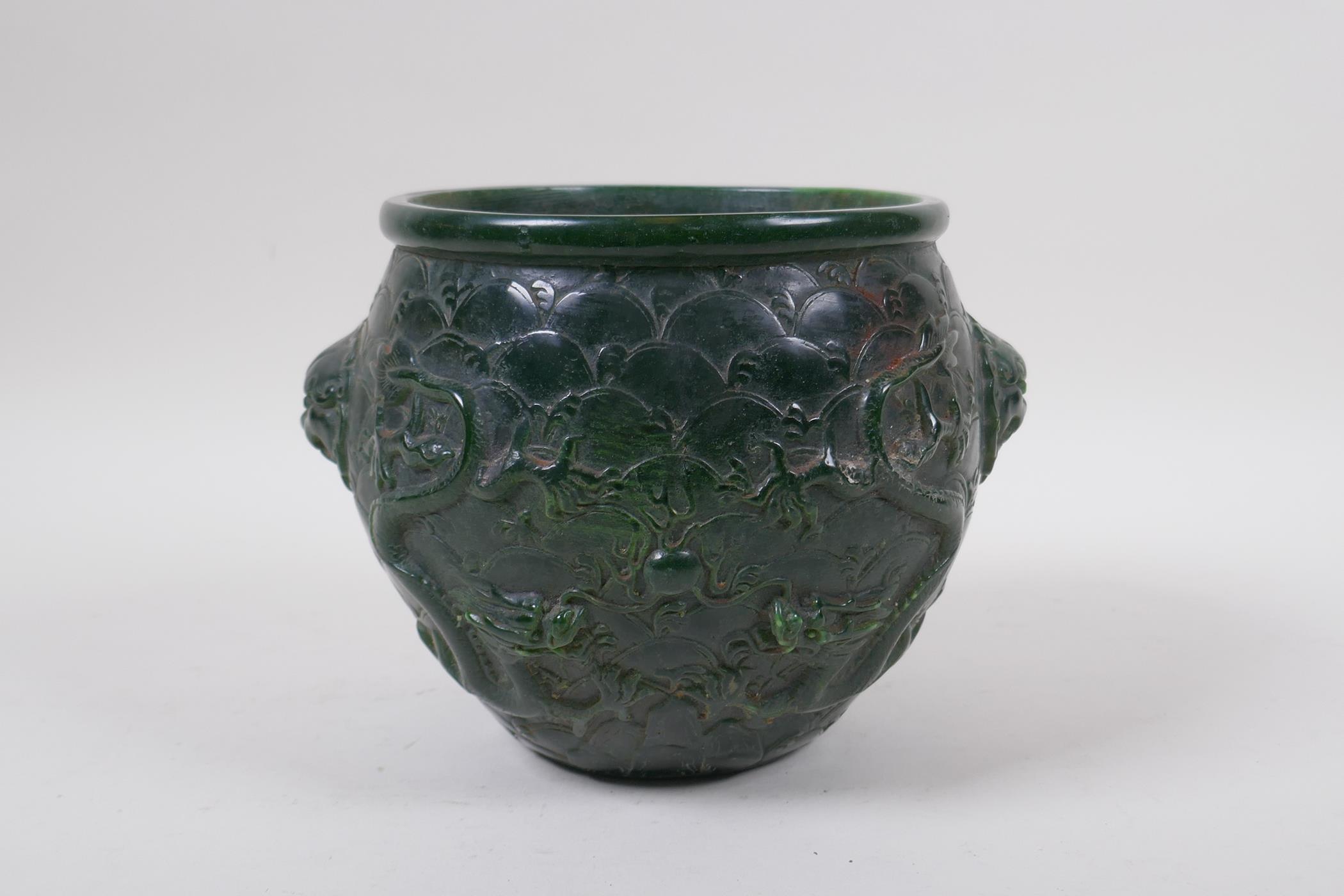 A Chinese reconstituted green hardstone jar with two lion mask handles and raised dragon decoration