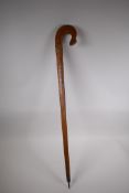 An East European walking stick with carved and stained Christian iconography decoration, 90cm long