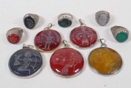 Five Middle Eastern intaglio stone pendants carved with traditional archaic designs in white metal