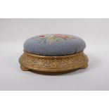 An antique gilt footstool with floral embossed pad, 30cm diameter