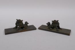 A pair of Chinese bronze scroll weights with decorative characters and fo dog mounts, 4 x 11cm