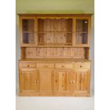 A pine dresser, the upper section with two glazed door flanking open shelves, the base with four