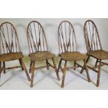 A set of four hoop back Windsor chairs with high backs and shaped solid elm seats, raised on