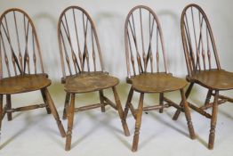 A set of four hoop back Windsor chairs with high backs and shaped solid elm seats, raised on