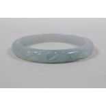 A Chinese mottled grey jade bangle with carp and ruyi decoration, 7cm diameter