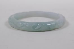 A Chinese mottled grey jade bangle with carp and ruyi decoration, 7cm diameter