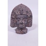 An antique Eastern/Tibetan black glazed terracotta votive Buddhistic mask, with flaming halo and