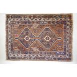An antique terracotta ground Persian wool village rug, with a twin geometric medallion design, AF,