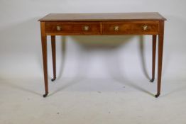 A C19th inlaid mahogany two drawer writing table with brass ring handles raised on square tapering