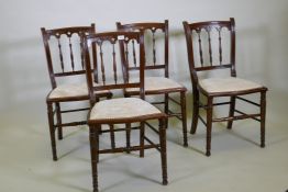 Four C19th beechwood and walnut side chairs with Gothic style backs, raised on turned tapering